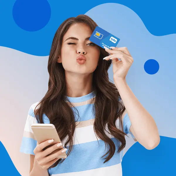 Woman in a striped shirt blowing a kiss while holding a Tello SIM card and phone