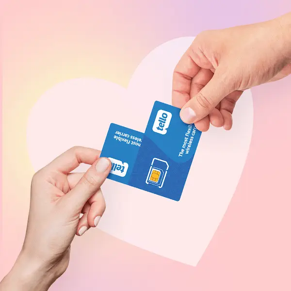 Two hands passing a Tello SIM card back and forth over a pink heart shape