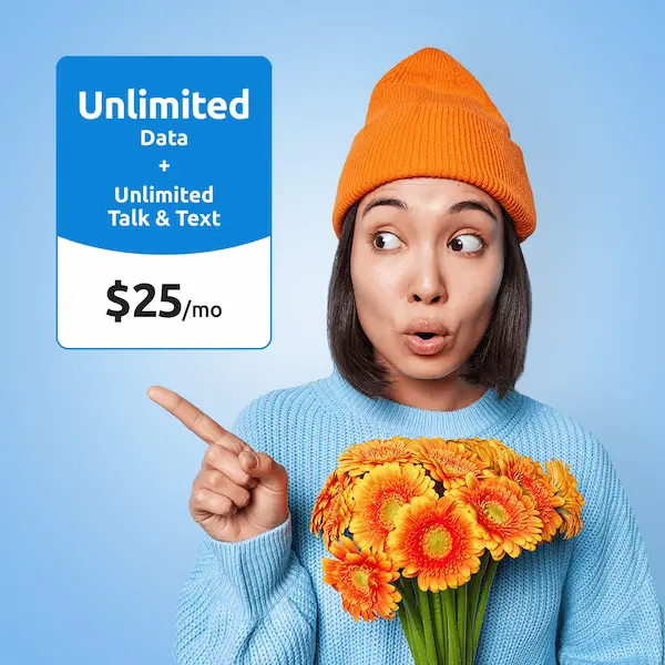 Woman in an orange beanie pointing at an "Unlimited Data + Unlimited Talk & Text, $25/mo" price card while holding orange flowers